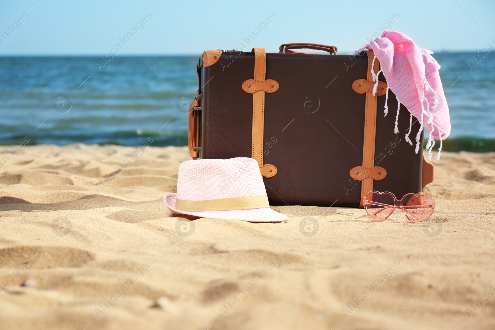 Photo of Suitcase and beach accessories on sand near sea. Space for text