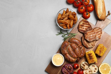 Photo of Flat lay composition with barbecued meat and vegetables on light table. Space for text