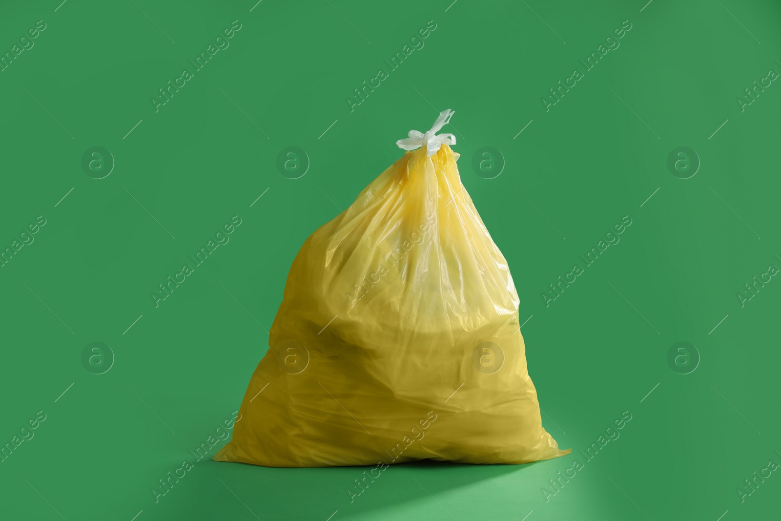 Photo of Trash bag full of garbage on green background