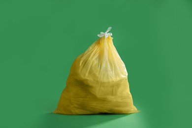 Trash bag full of garbage on green background