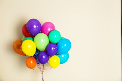 Photo of Bunch of bright balloons on color background with space for design