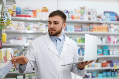 Photo of Professional pharmacist with laptop in modern drugstore