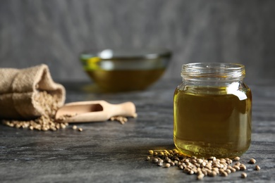 Photo of Jar with hemp oil on grey table