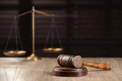 Wooden gavel and scales of justice on table against blurred background. Space for text