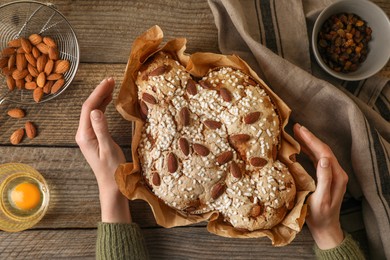 Woman with delicious Italian Easter dove cake (traditional Colomba di Pasqua) at wooden table, top view