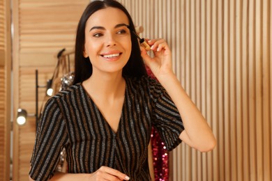 Photo of Beautiful young woman applying mascara in dressing room