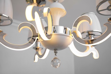Stylish chandelier on ceiling in room, closeup