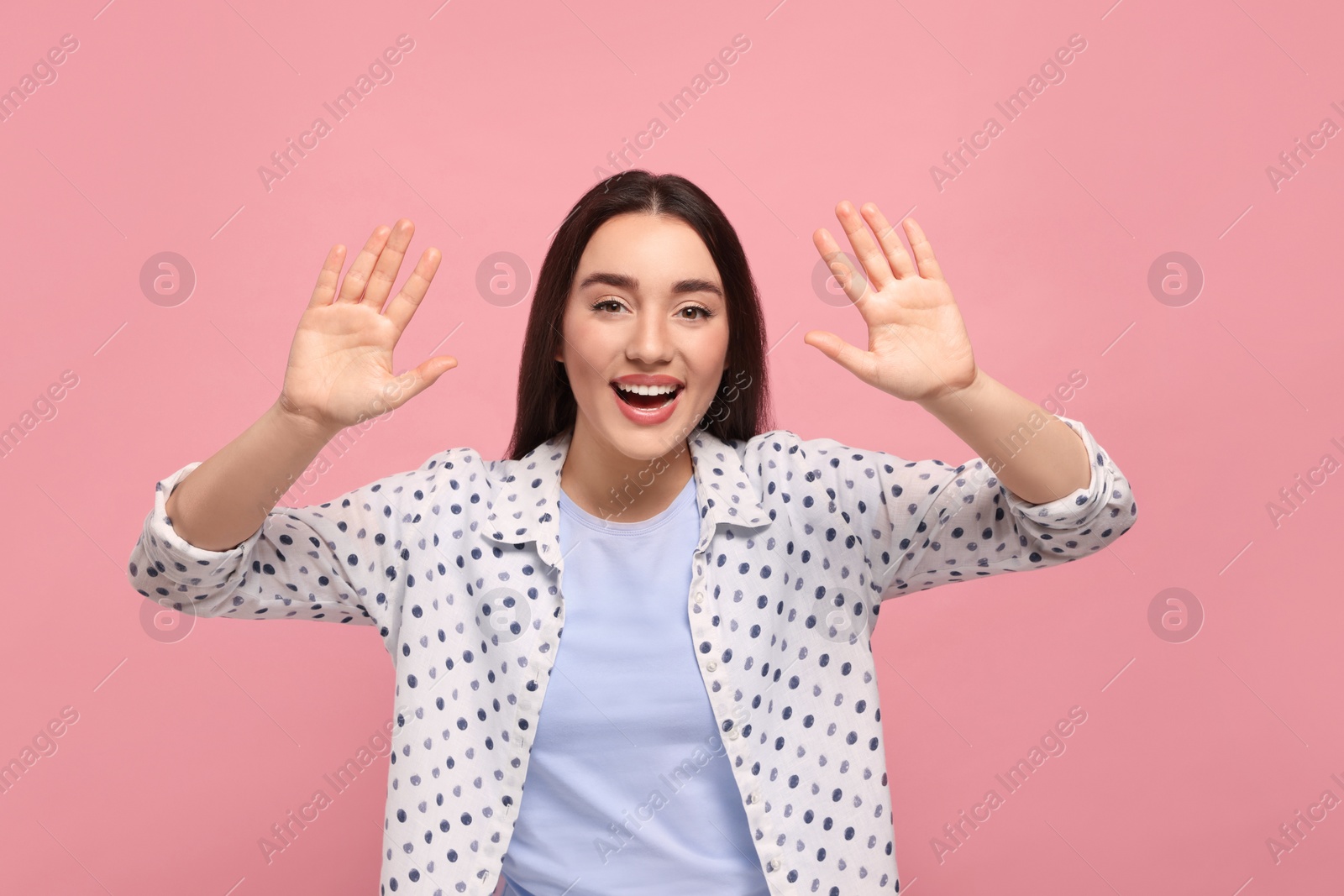 Photo of Happy woman giving high five with both hands on pink background