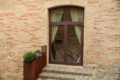 Building entrance with arched wooden door and houseplants