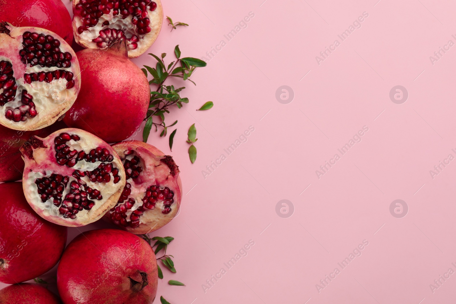 Photo of Flat lay composition with ripe pomegranates on pink background. Space for text