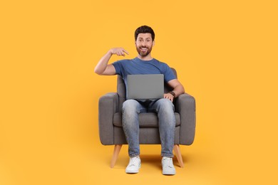 Photo of Emotional man with laptop sitting in armchair against yellow background