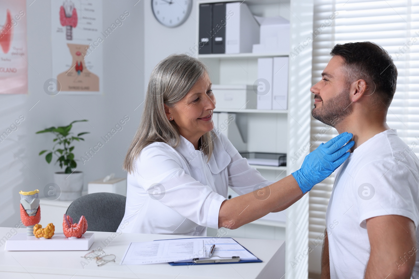 Photo of Endocrinologist examining thyroid gland of patient at table in hospital