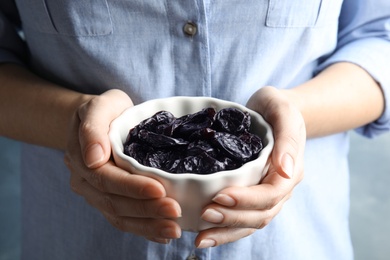 Photo of Woman holding bowl of dried plums, closeup. Healthy fruit