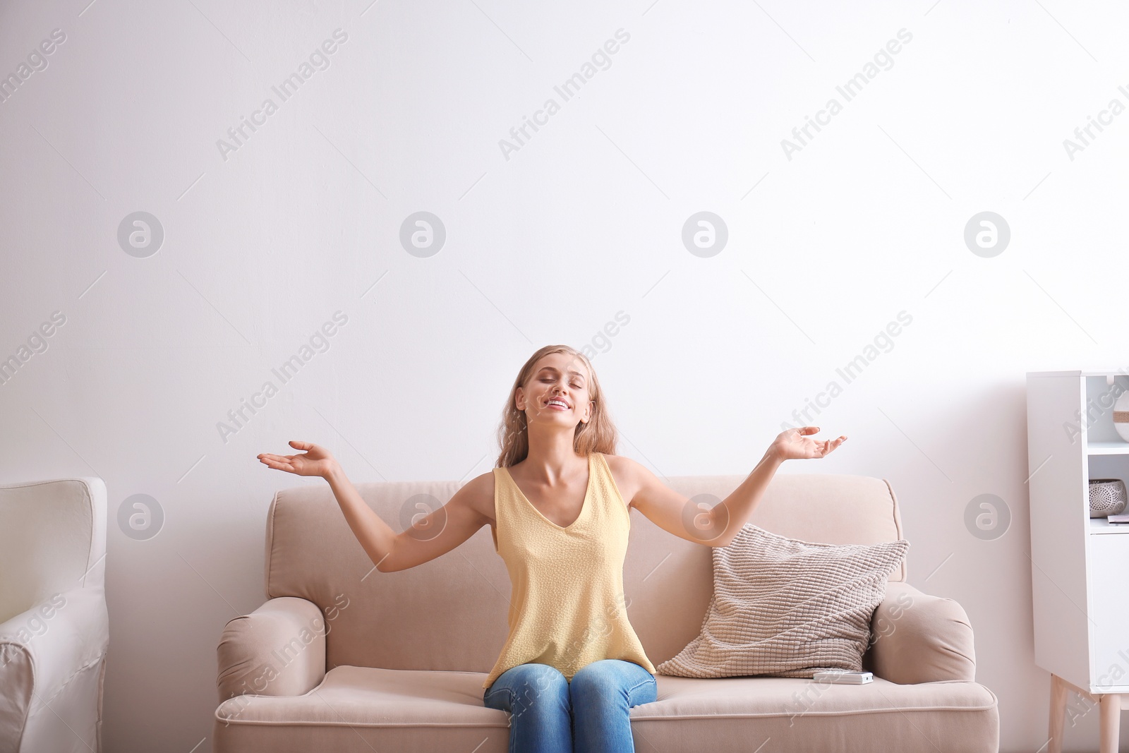 Photo of Young woman relaxing under air conditioner at home