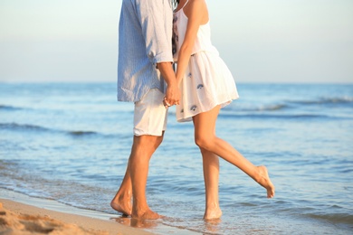 Photo of Happy young couple holding hands at beach on sunny day, closeup