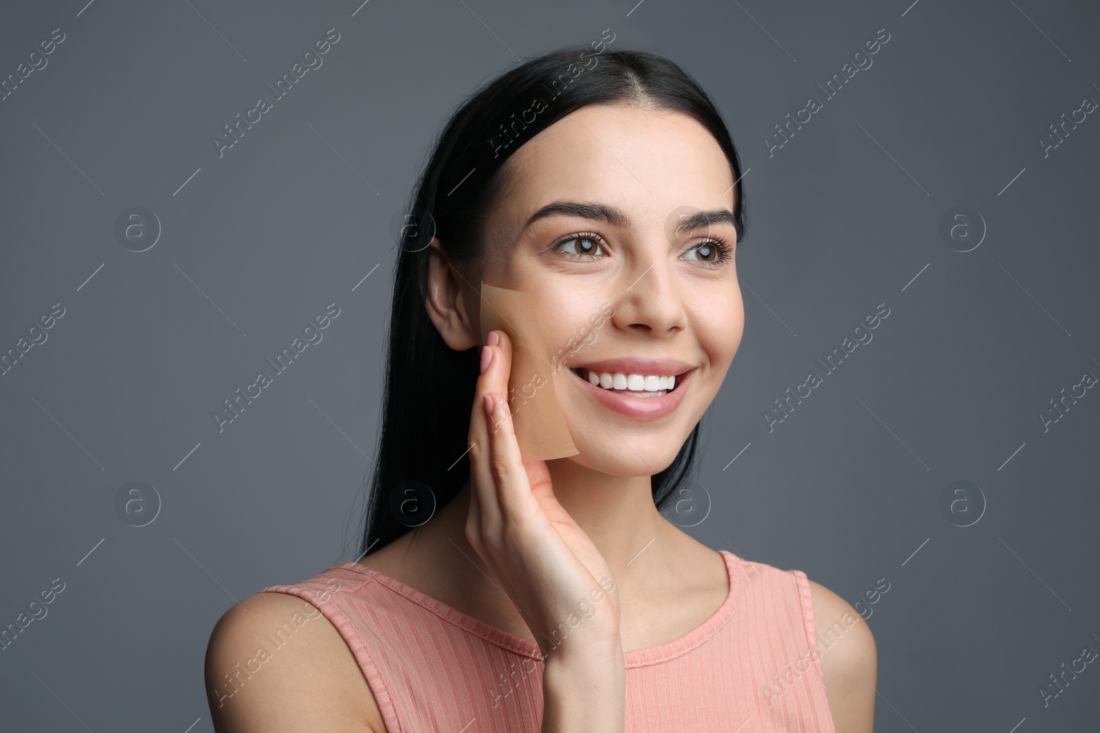 Photo of Beautiful woman using mattifying wipe on grey background