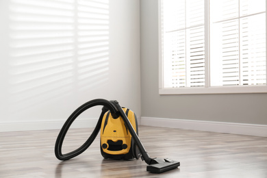 Photo of Modern yellow vacuum cleaner on floor indoors
