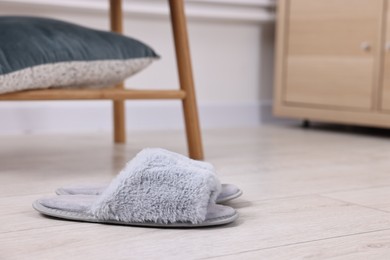 Photo of Grey soft slippers on light wooden floor indoors, closeup. Space for text