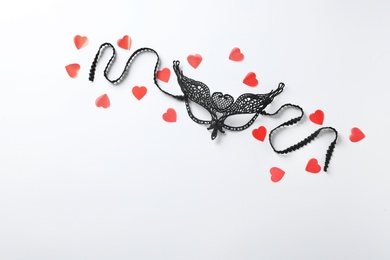 Black lace mask for sexual role play and red hearts on white background