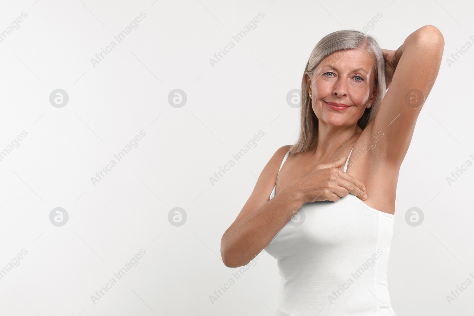 Photo of Beautiful senior woman doing breast self-examination on white background, space for text