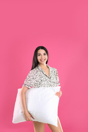 Young woman with pillow on pink background