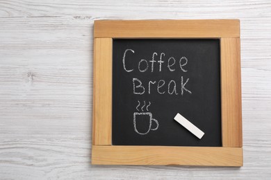 Photo of Blackboard with phrase Coffee Break and piece of chalk on white wooden table, top view