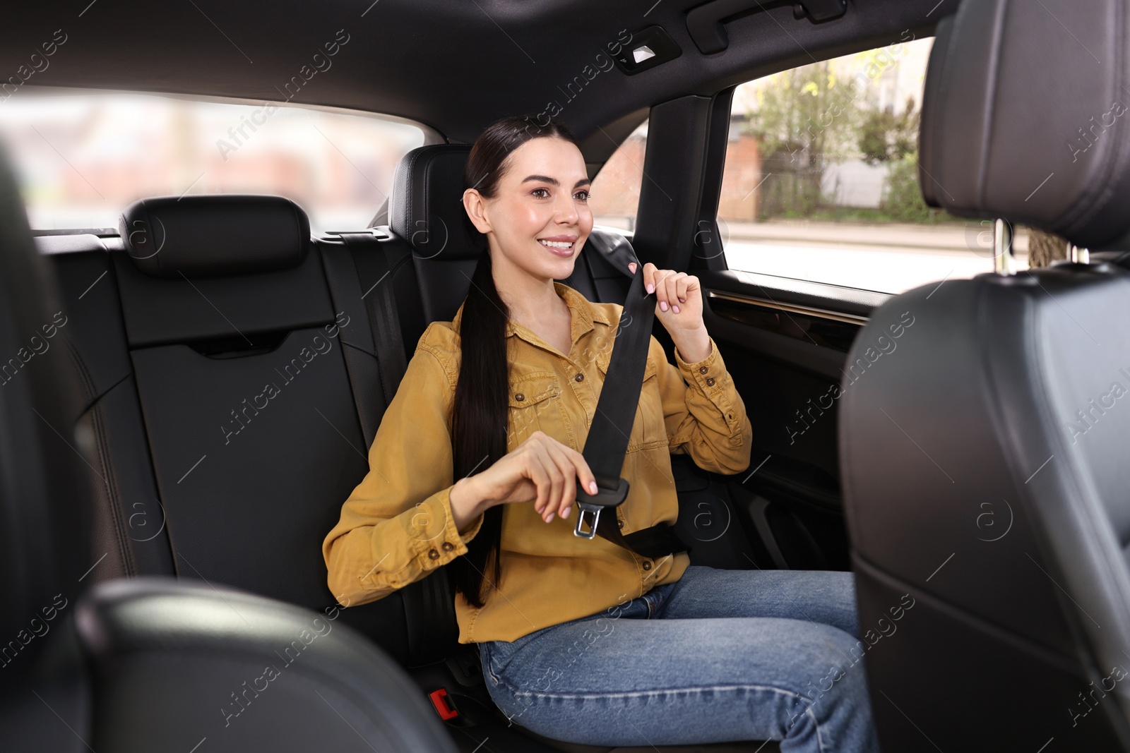 Photo of Woman fastening safety seat belt inside modern car