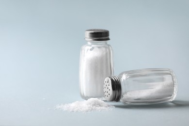 Photo of Natural salt in shakers on color background, space for text