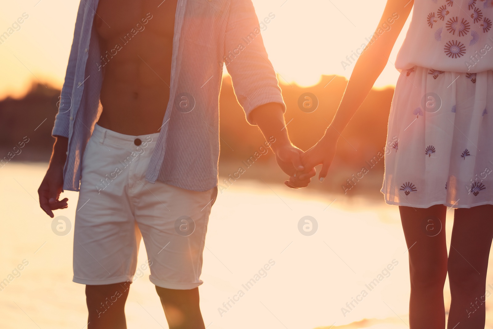 Photo of Happy young couple holding hands at beach on sunny day, closeup