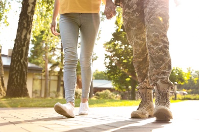 Man in military uniform walking with his girlfriend at sunny park, closeup