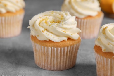 Photo of Delicious cupcakes with white cream and lemon zest on gray table, closeup