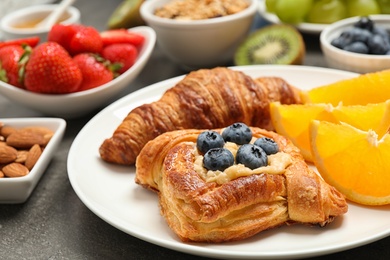 Photo of Delicious pastries and orange slices on grey table, closeup. Buffet service