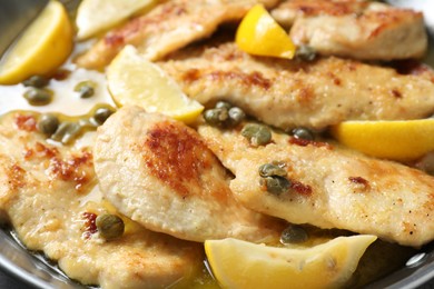 Photo of Delicious chicken piccata with lemons in pot, closeup