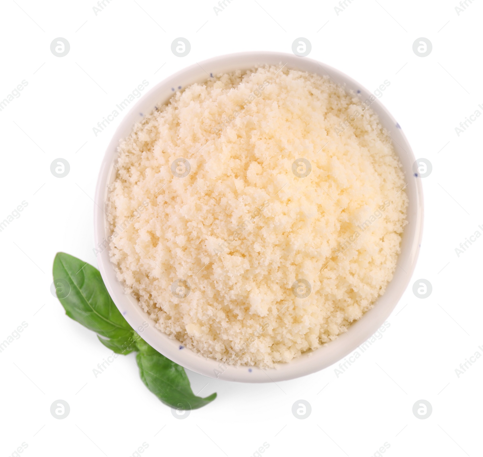 Photo of Delicious grated parmesan cheese in bowl and basil on white background, top view