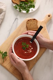 Man with delicious tomato soup at light marble table, top view