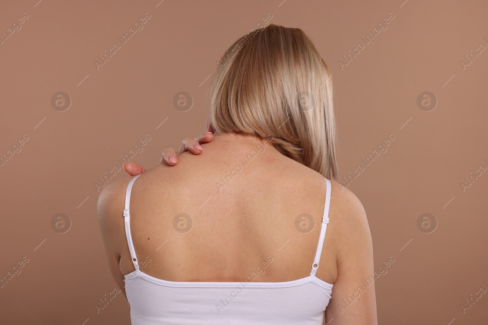 Photo of Woman suffering from pain in her neck on beige background, back view