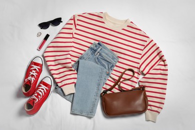 Photo of Pair of stylish red sneakers, clothes and accessories on white fabric, flat lay