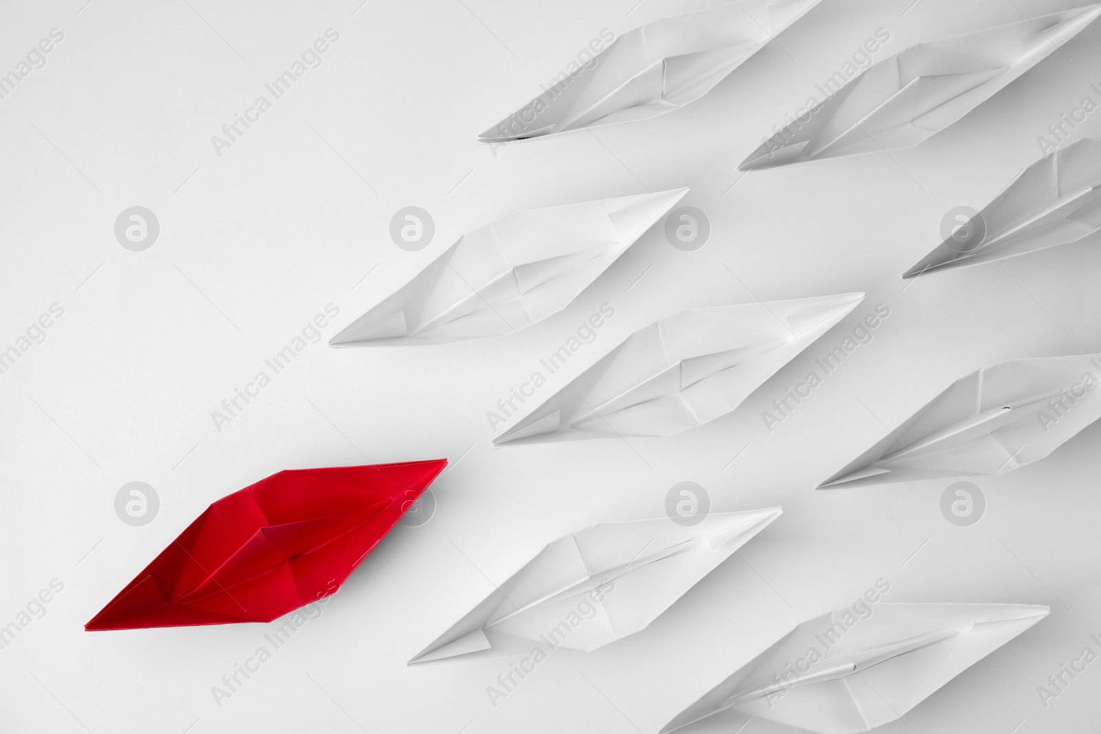 Photo of Group of paper boats following red one on white background, flat lay. Leadership concept