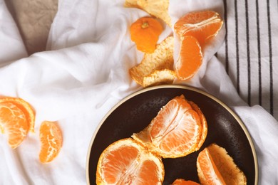 Photo of Fresh ripe tangerines on colorful cloth, flat lay