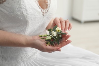 Photo of Bride holding boutonniere for her groom on blurred background, closeup