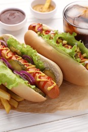 Photo of Delicious hot dogs with lettuce, onion and pickle on white wooden table, closeup