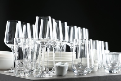 Photo of Set of empty glasses and dishware on table against black background