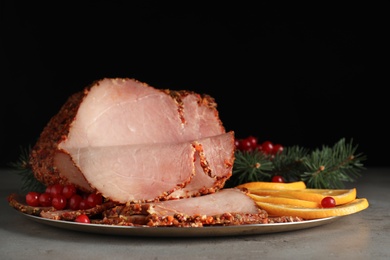 Delicious ham served for Christmas dinner on grey table against black background