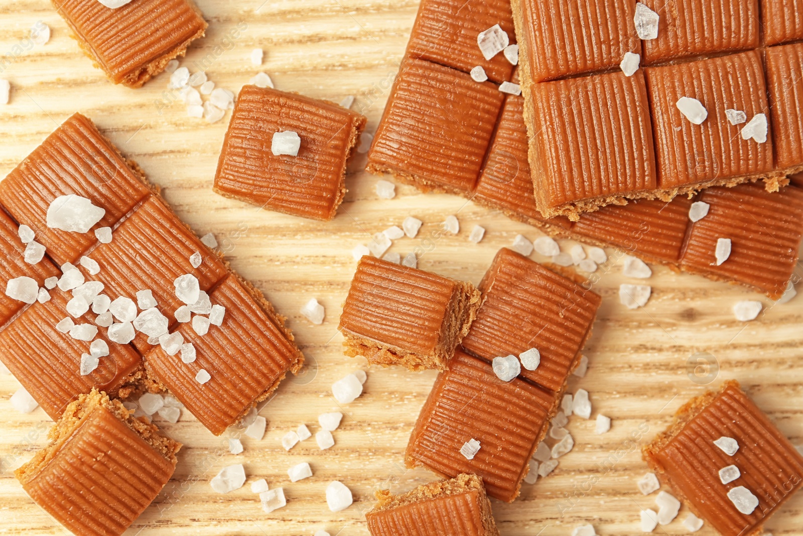 Photo of Delicious caramel candies with salt on wooden table