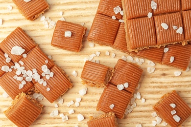 Delicious caramel candies with salt on wooden table