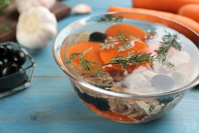 Photo of Delicious aspic with meat and vegetables served on light blue wooden table, closeup