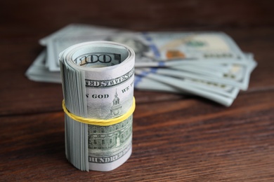 Many dollar banknotes on wooden table, closeup. Space for text