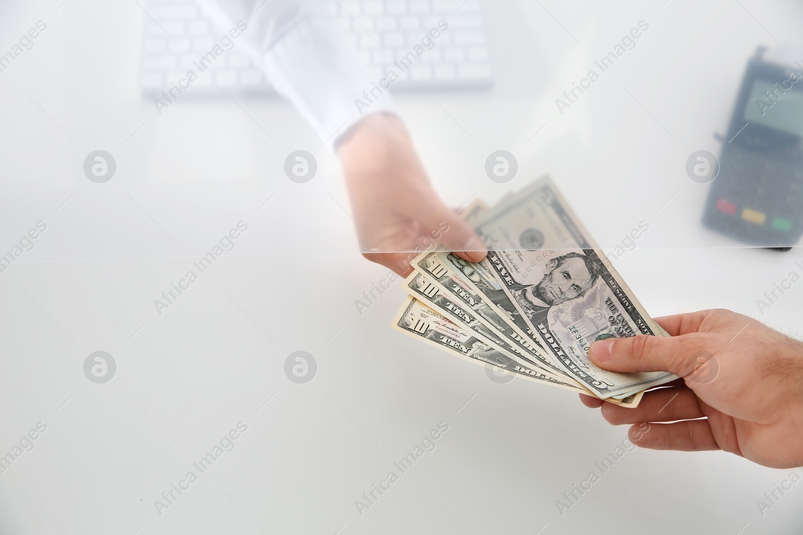 Photo of Man giving money to teller at cash department window, top view