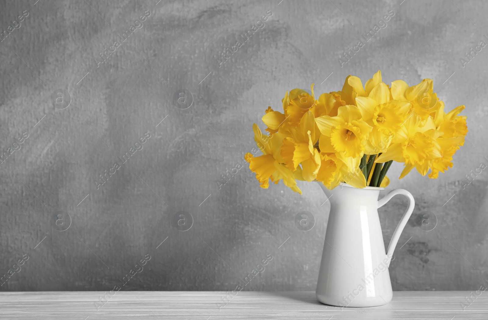 Image of Color of the year 2021. Bouquet of yellow daffodils on table against grey background, space for text