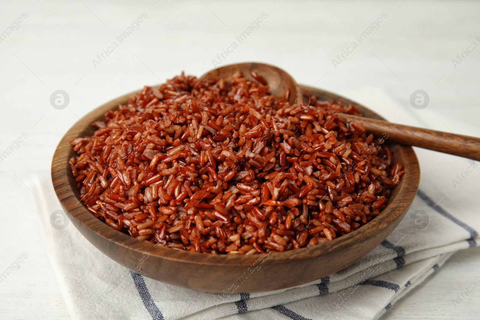 Photo of Wooden bowl with delicious cooked brown rice on white table